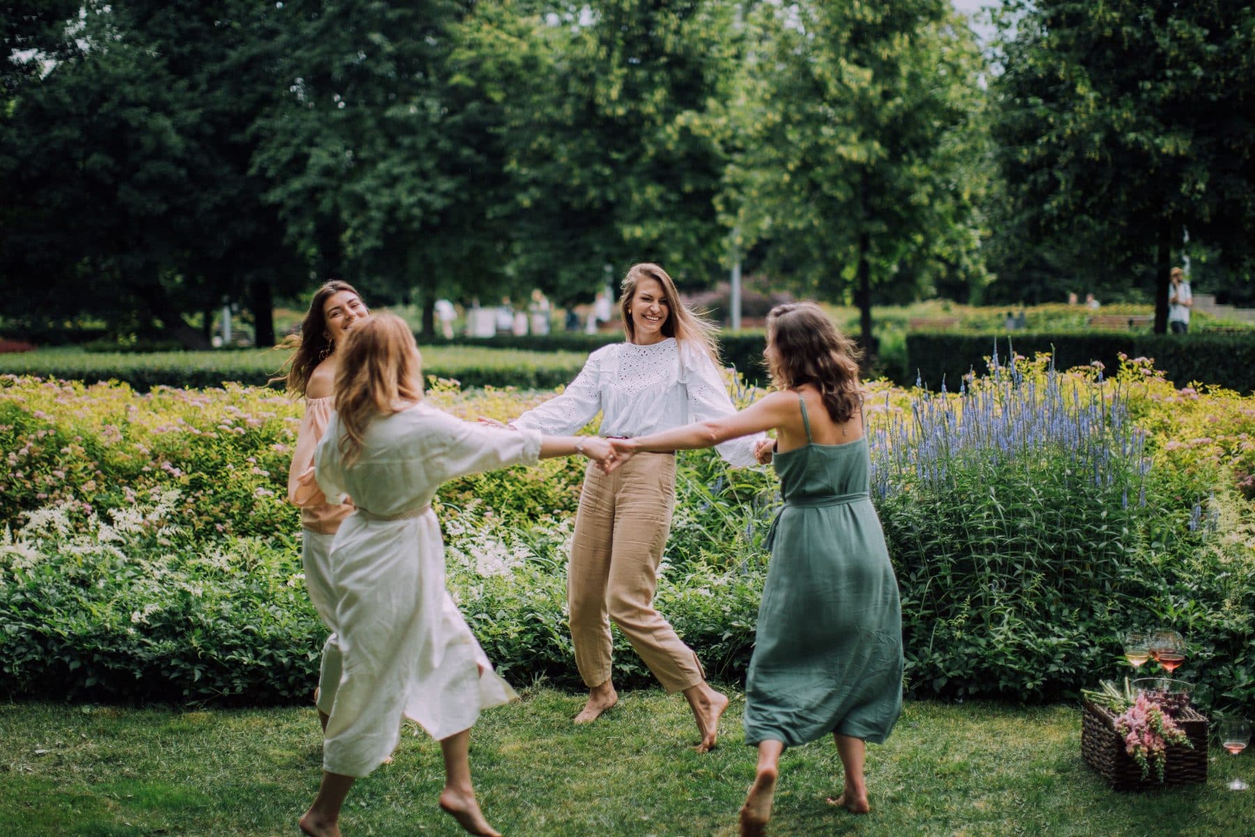 Women dancing in a ring on the grass in a summer garden.
